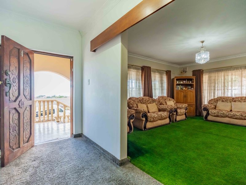 Entrance foyer leading into a spacious living area with a feature carved timber door and access to an outdoor balcony.