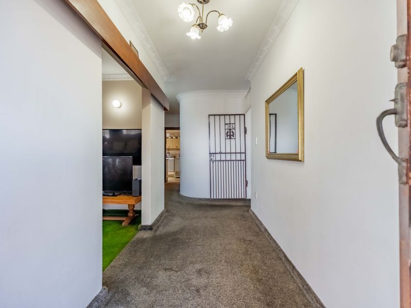 A functional hallway featuring decorative ceiling cornicing and a security gate, providing access to adjacent living areas.