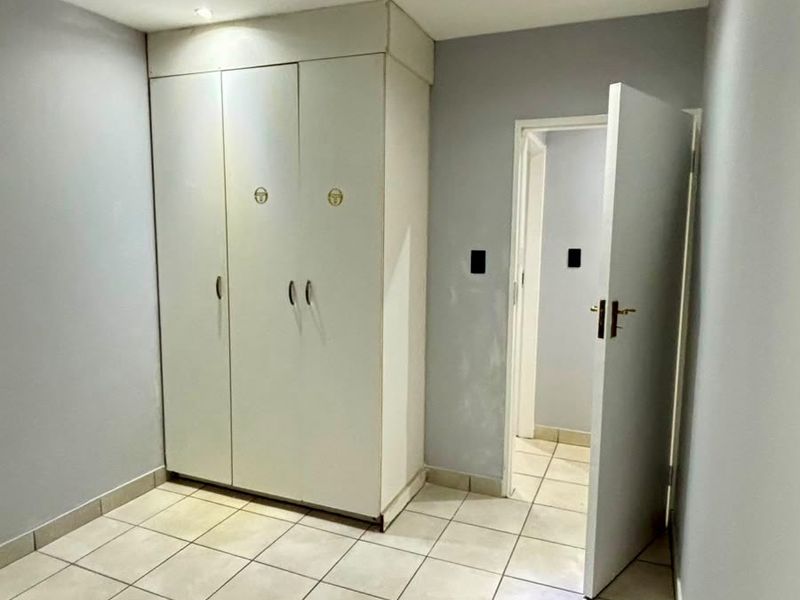 A vacant bedroom featuring tiled flooring, recessed lighting, and a built-in wardrobe with neutral wall finishes.