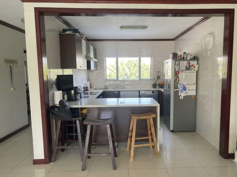 A functional U-shaped kitchen featuring a breakfast bar, tiled backsplash, and neutral floor tiles, offering a practical layout for daily meal preparation.
