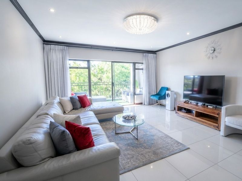 A bright and modern living room featuring polished porcelain floor tiles, crown molding, recessed lighting, and large sliding glass doors leading to a balcony.