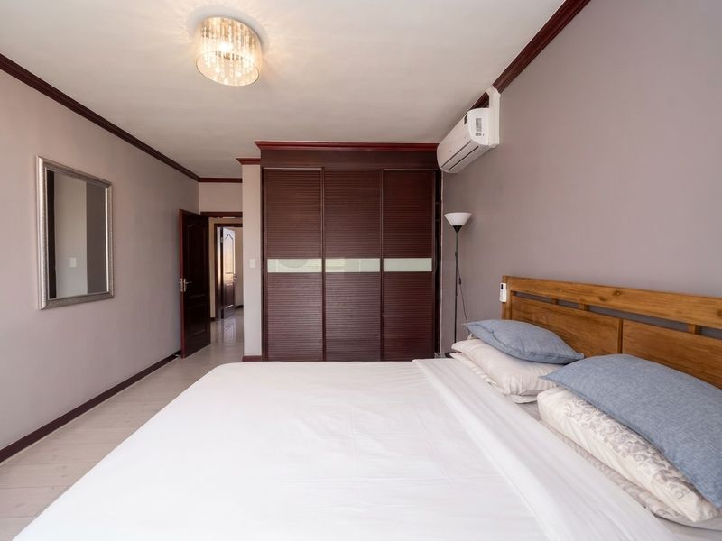 A well-maintained bedroom featuring a large built-in wardrobe, split-system air conditioning, and crown molding details.