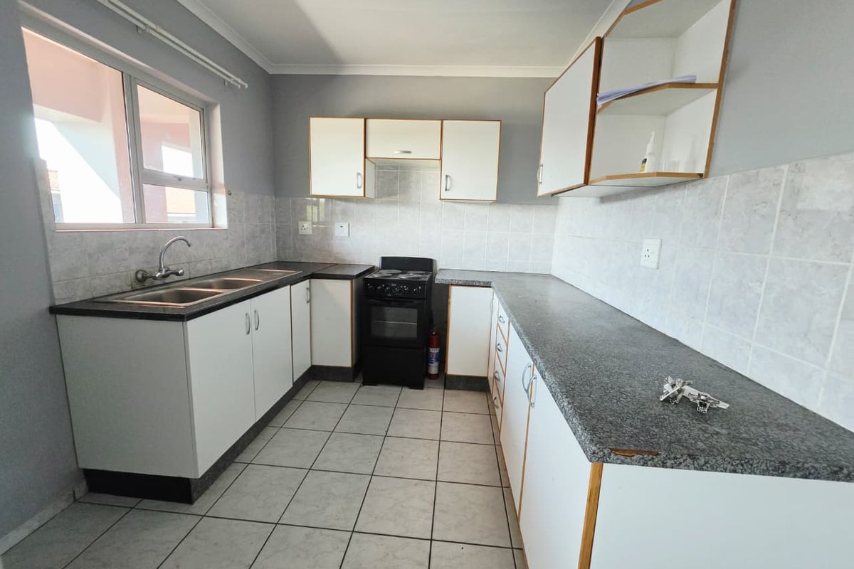 A functional kitchen featuring white cabinetry, laminate countertops, a tiled backsplash, and a freestanding stove, offering a clean and practical workspace.