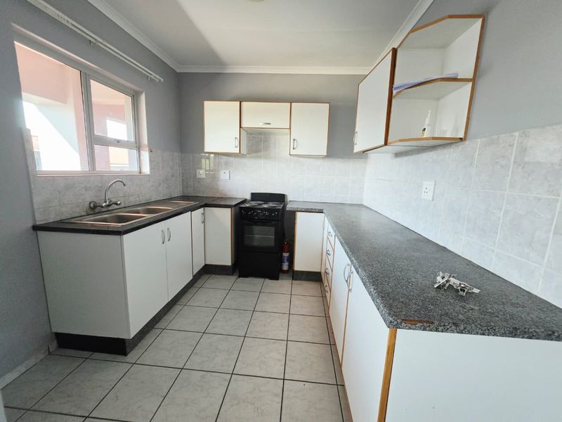 A functional kitchen featuring white cabinetry, laminate countertops, a tiled backsplash, and a freestanding stove, offering a clean and practical workspace.