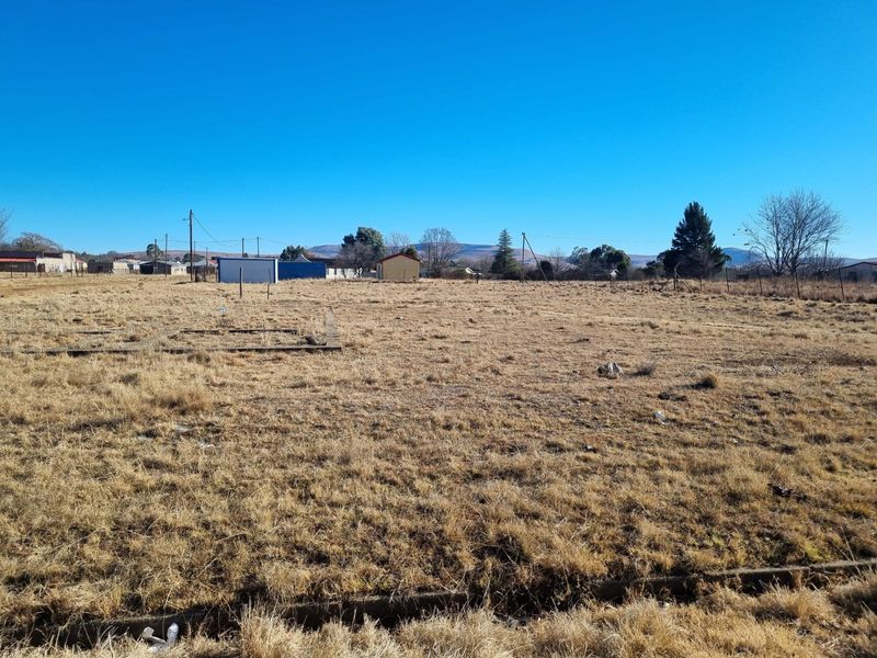 A vacant residential plot featuring a concrete foundation slab and perimeter fencing, offering a clear space for future development.