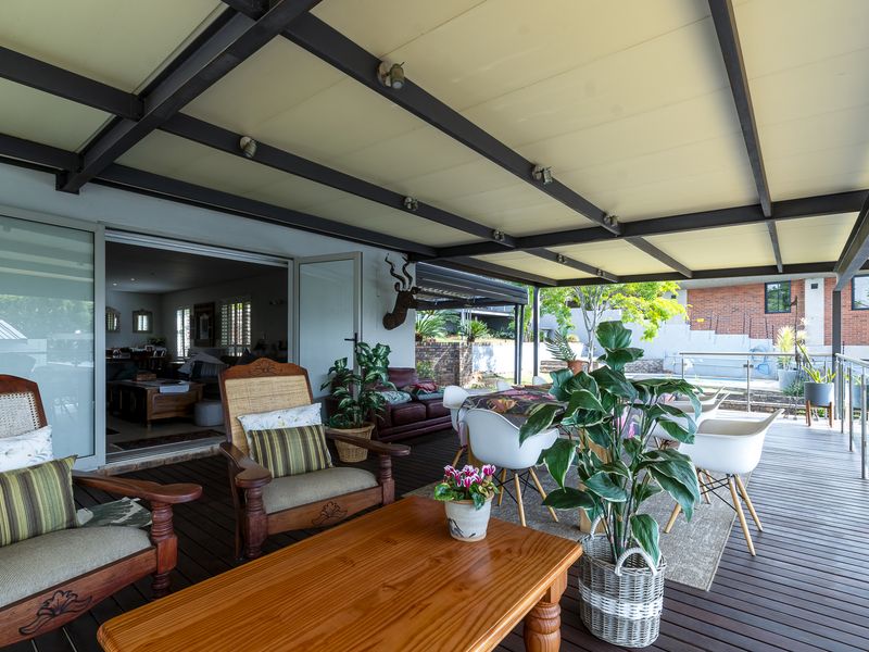 Spacious covered patio featuring timber decking, exposed steel beam ceiling, and seamless access to the interior living area through large sliding glass doors.
