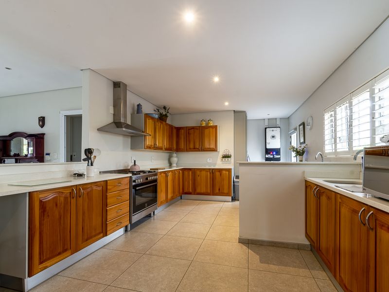Spacious kitchen featuring warm wooden cabinetry, stainless steel appliances, tiled flooring, and integrated inverter system, offering a functional and well-maintained cooking space.