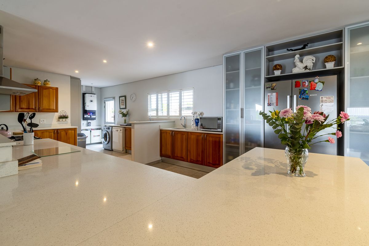 Spacious open-plan kitchen featuring quartz countertops, warm wooden cabinetry, integrated storage, and a dedicated laundry area with modern solar power infrastructure.