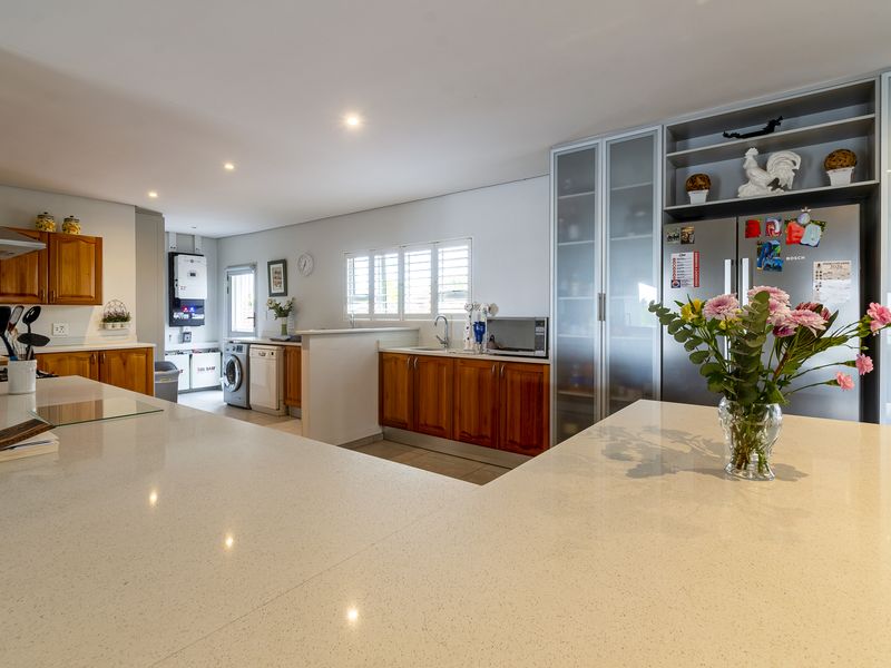 Spacious open-plan kitchen featuring quartz countertops, warm wooden cabinetry, integrated storage, and a dedicated laundry area with modern solar power infrastructure.