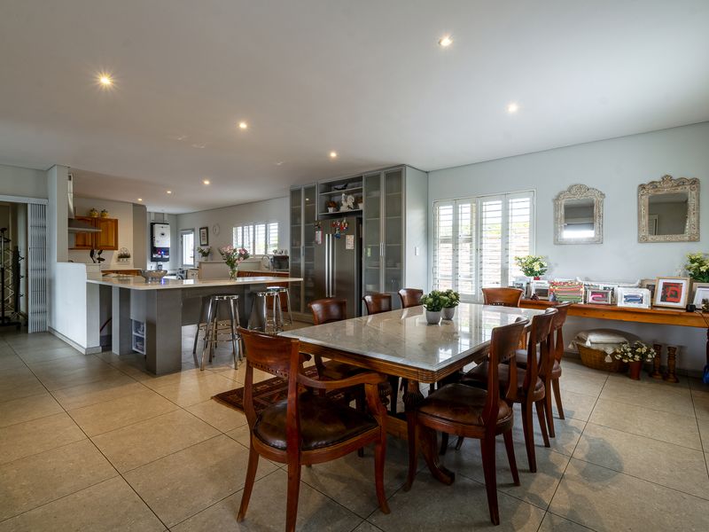 Spacious open-plan living and dining area featuring a modern kitchen island, tiled flooring, recessed lighting, and plantation shutters throughout.