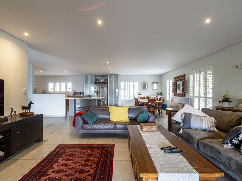Spacious open-plan living area featuring tiled floors, recessed lighting, and a modern kitchen with a central island, seamlessly flowing into the dining space.