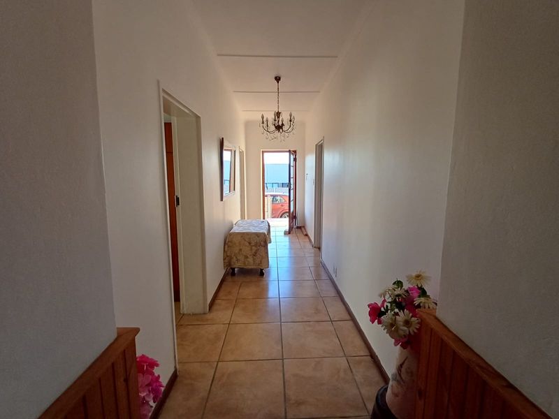 A bright, tiled hallway featuring timber wainscoting and a central light fixture, providing access to various rooms within the home.
