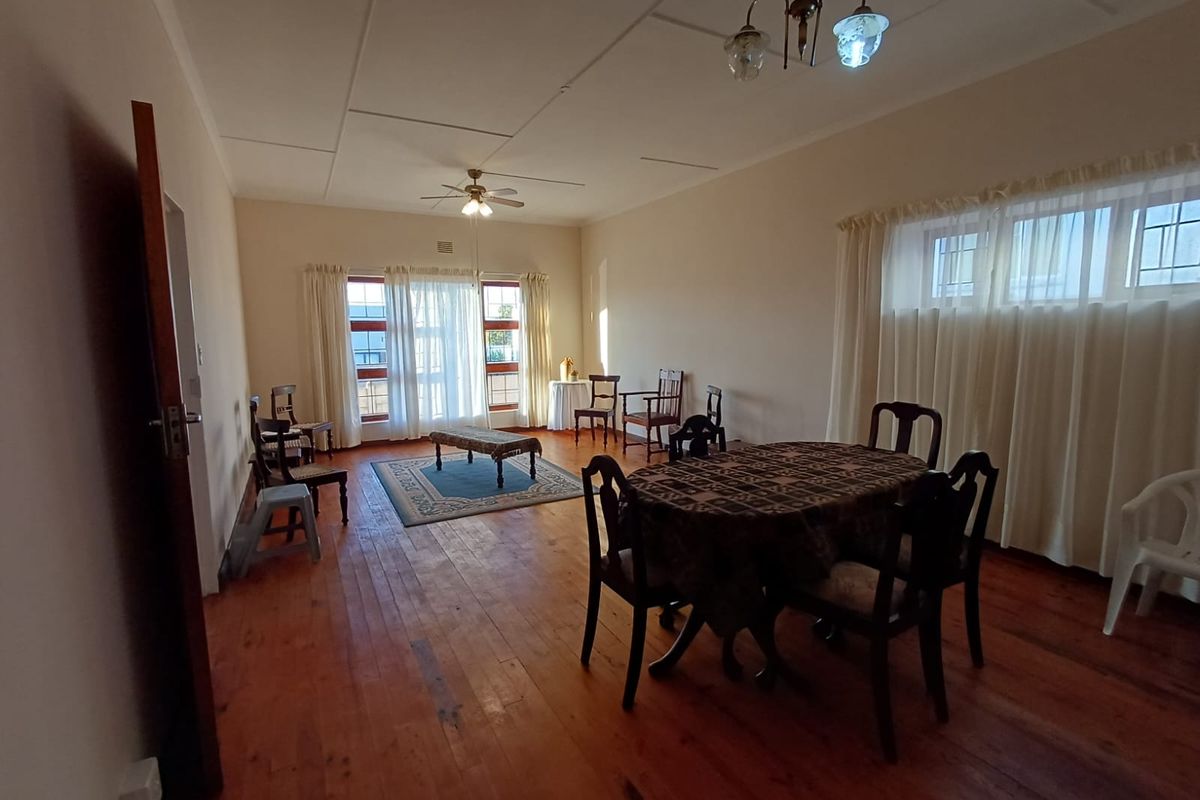Spacious living and dining area featuring original hardwood flooring, neutral walls, and large windows allowing for natural light.