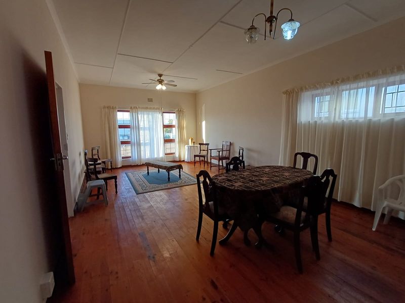 Spacious living and dining area featuring original hardwood flooring, neutral walls, and large windows allowing for natural light.