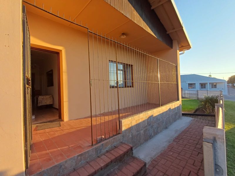 A covered front patio area featuring tiled flooring, stone cladding, and security bars, providing a secure entrance to the home.