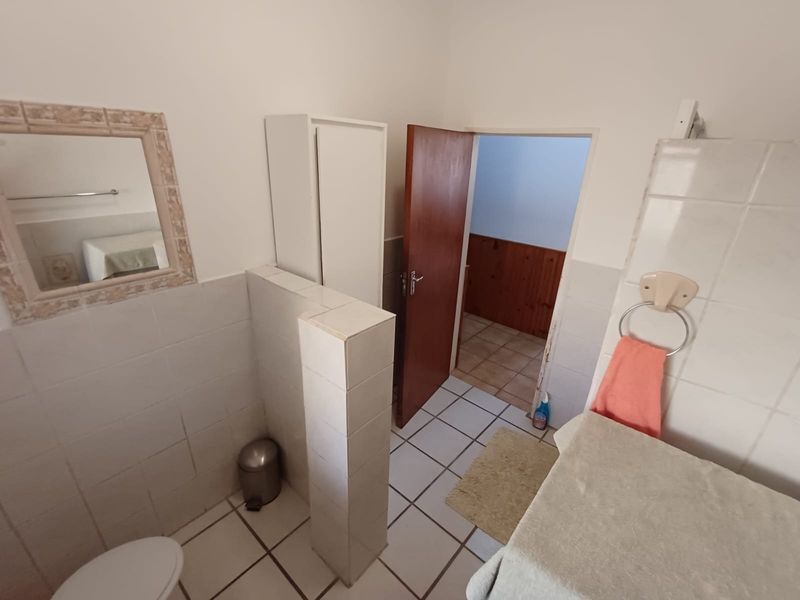 A dated bathroom featuring tiled flooring, a built-in vanity partition, and wall-mounted fixtures, offering potential for a modern renovation.