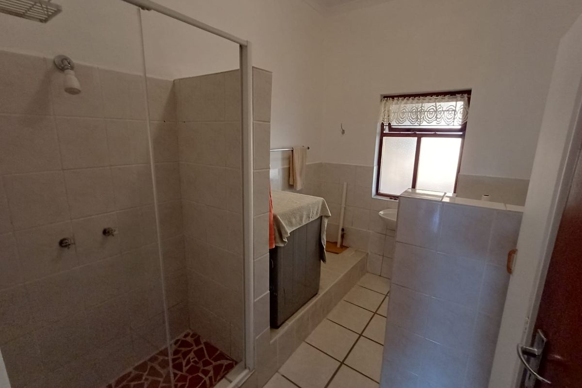 A functional bathroom featuring a walk-in shower with a glass enclosure, tiled walls, and tiled flooring on a raised platform area.