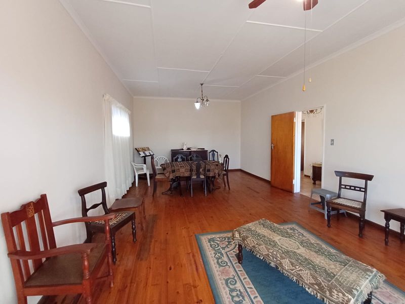 Spacious living area featuring polished timber flooring and a ceiling fan, offering a neutral canvas for potential interior updates.
