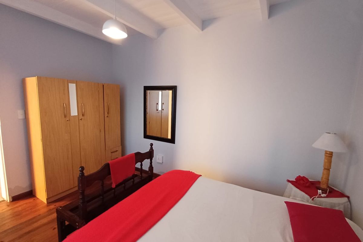 A bedroom featuring exposed timber ceiling beams and warm timber flooring, providing a cozy and traditional atmosphere.