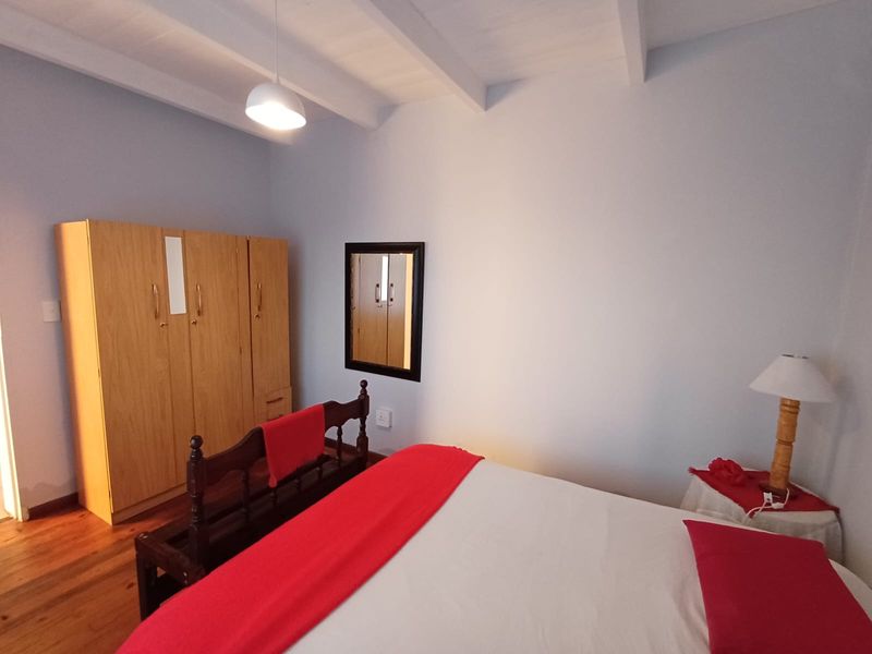 A bedroom featuring exposed timber ceiling beams and warm timber flooring, providing a cozy and traditional atmosphere.