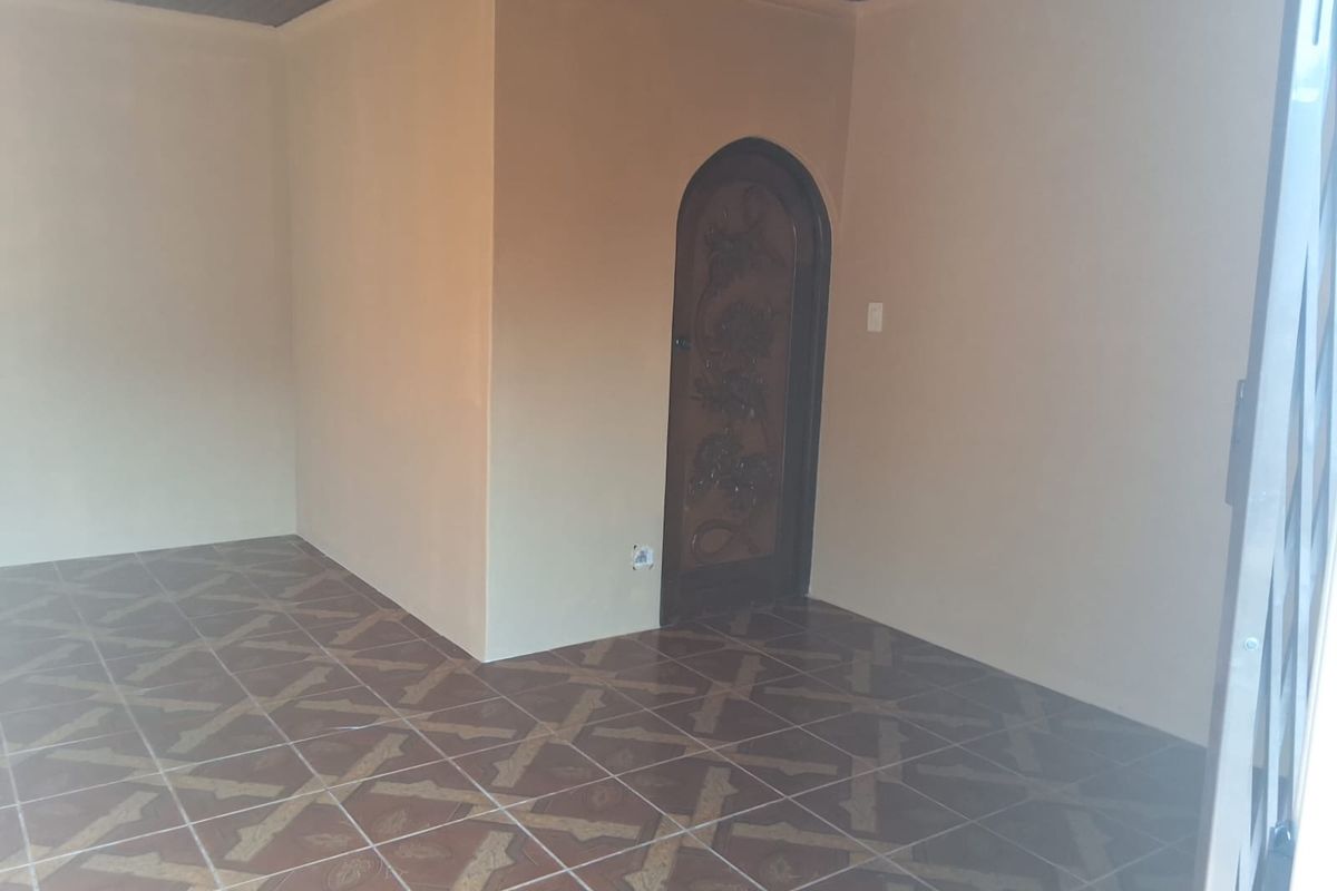 An empty living area featuring tiled flooring, a timber ceiling, and a decorative arched wooden door.
