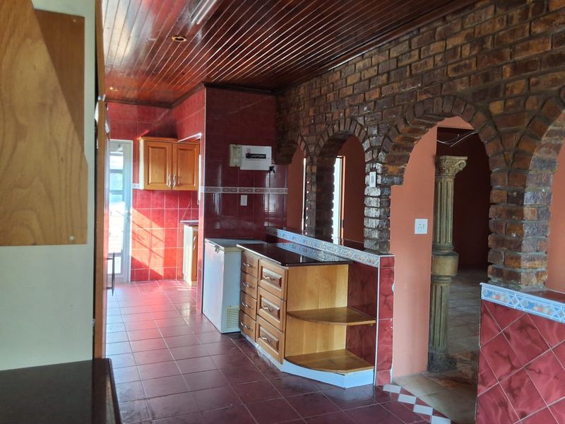 Kitchen area featuring timber ceiling, exposed brick archways, and tiled finishes, offering a unique layout with potential for modern renovation.