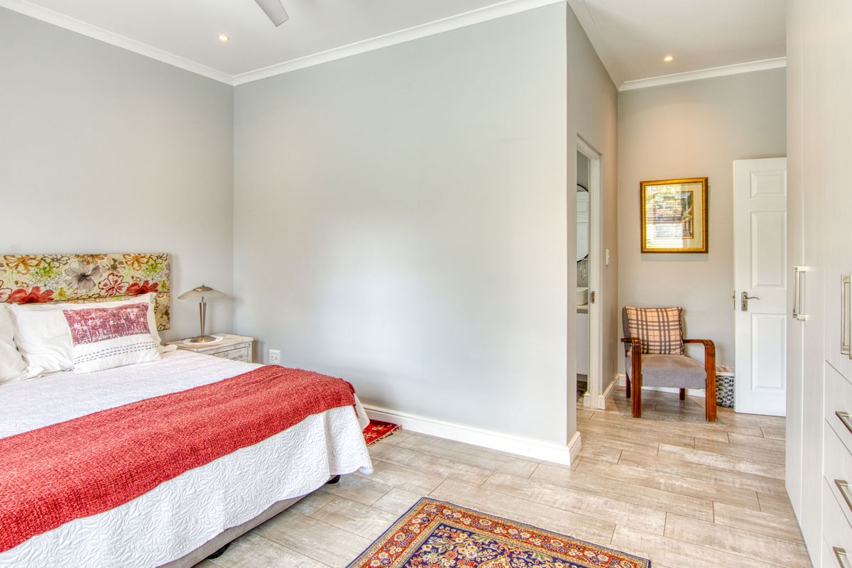 A well-maintained bedroom featuring neutral wall tones, tiled flooring, built-in storage, and direct access to an en-suite bathroom.
