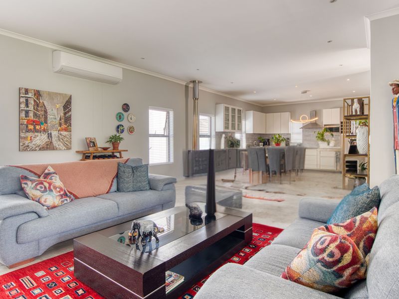 Spacious open-plan living and kitchen area featuring a wood-burning fireplace, split-system air conditioning, and modern cabinetry, creating a bright and functional living space.