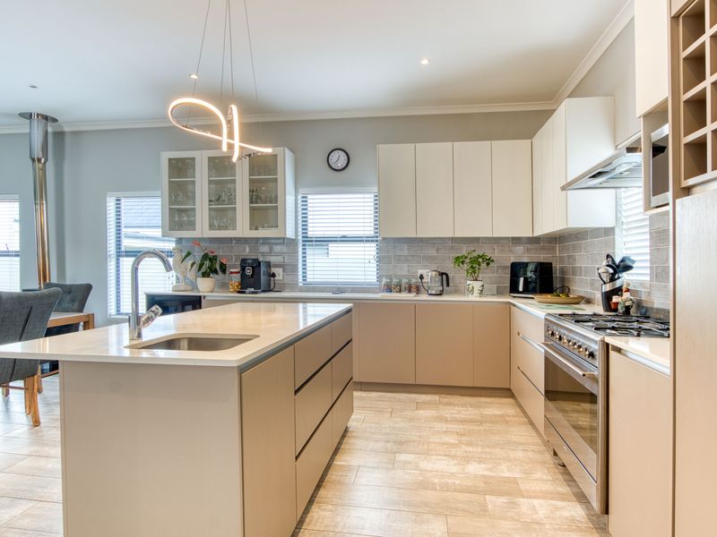 Modern kitchen featuring a central island, stone countertops, gas hob, built-in oven, and ample cabinetry with a stylish tiled backsplash.