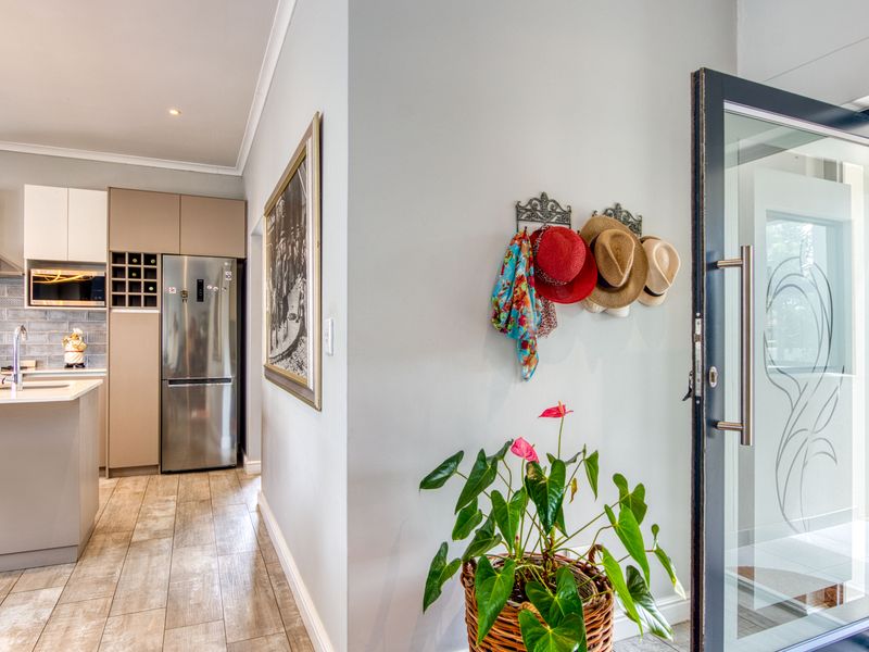 A modern kitchen featuring sleek cabinetry, a central island, and integrated appliances, seamlessly connected to the home entrance.