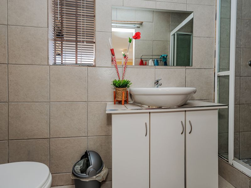 A functional bathroom featuring a vessel sink on a vanity cabinet, a wall-mounted mirror, and a separate shower enclosure with tiled walls.