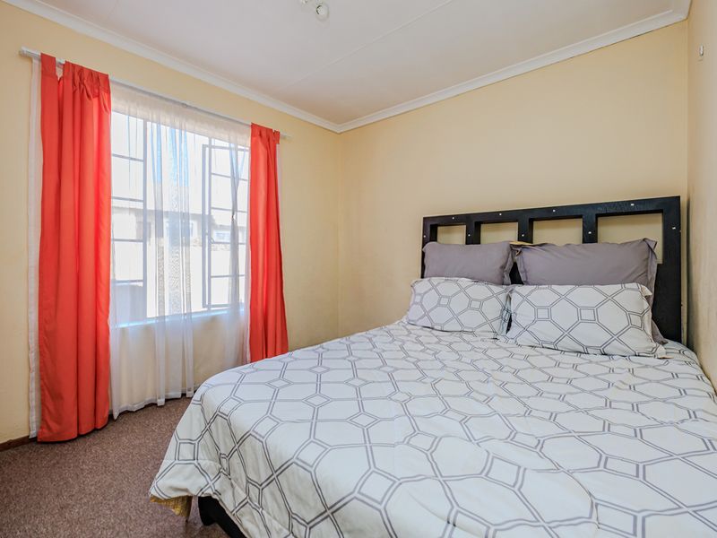 A standard bedroom featuring carpeted flooring, a window with natural light, and coved ceiling finishes.