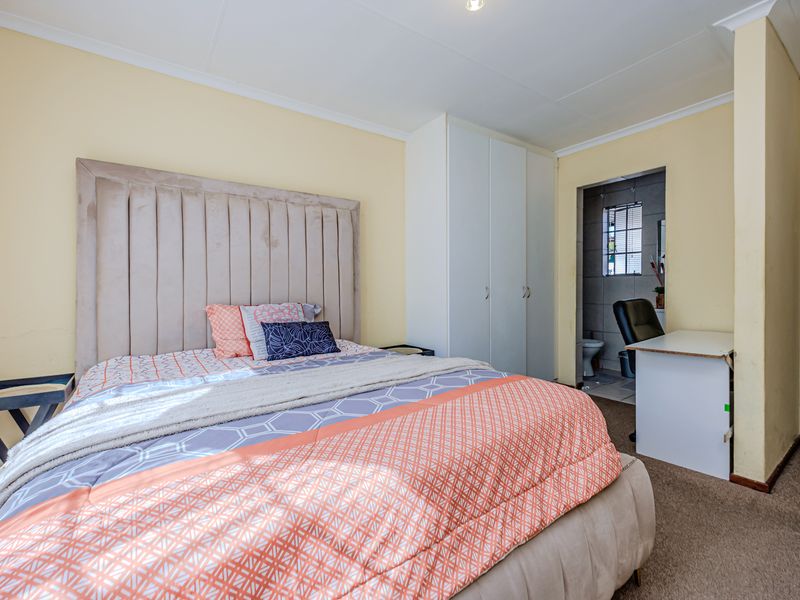 A bedroom featuring built-in cupboards, carpeted flooring, and direct access to an en-suite bathroom.