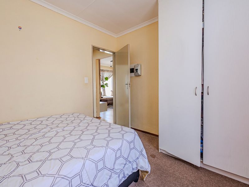 A bedroom featuring carpet flooring, a built-in wardrobe, and neutral wall paint, offering a functional space with potential for cosmetic updates.