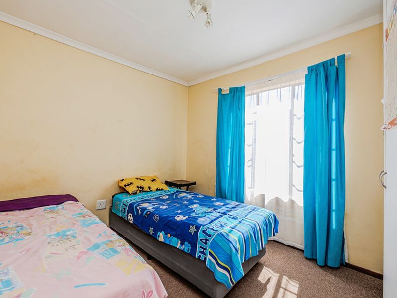 A standard bedroom featuring carpeted flooring, a window with curtains, and a built-in cupboard, requiring minor cosmetic updates to the wall finishes.