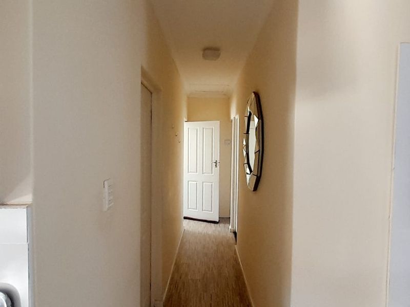 A functional hallway connecting interior spaces, featuring neutral wall finishes, laminate flooring, and multiple internal doors.