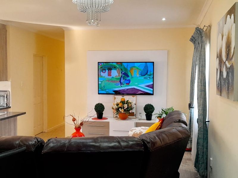 An open-plan living area featuring a modern kitchen with built-in cabinetry and a breakfast bar, seamlessly connected to a comfortable lounge space.