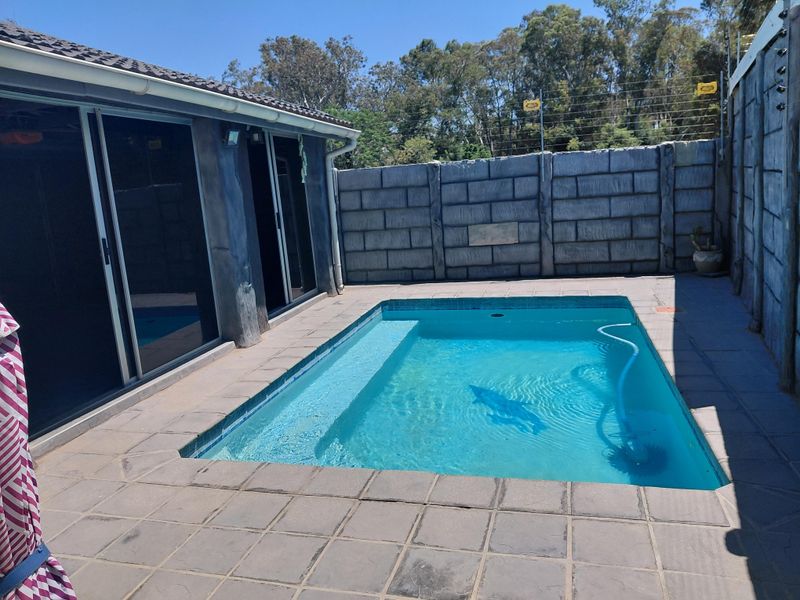 Outdoor pool area featuring a tiled surround, precast concrete boundary walls with electric fencing, and direct access to the home via sliding glass doors.