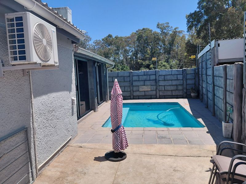 Outdoor pool area featuring a swimming pool, tiled patio, and secure perimeter wall with electric fencing, adjacent to the main house structure.