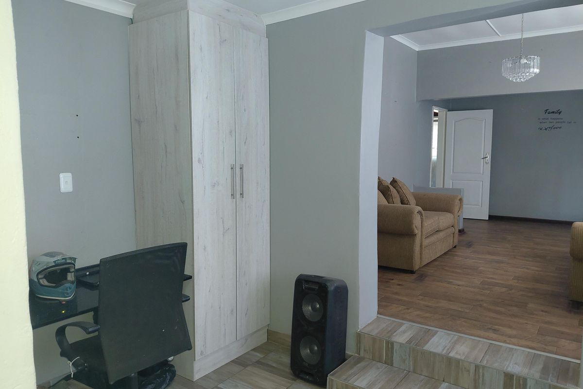 A multi-level living area featuring a built-in wardrobe, laminate and tiled flooring, and a transition between two distinct living spaces.