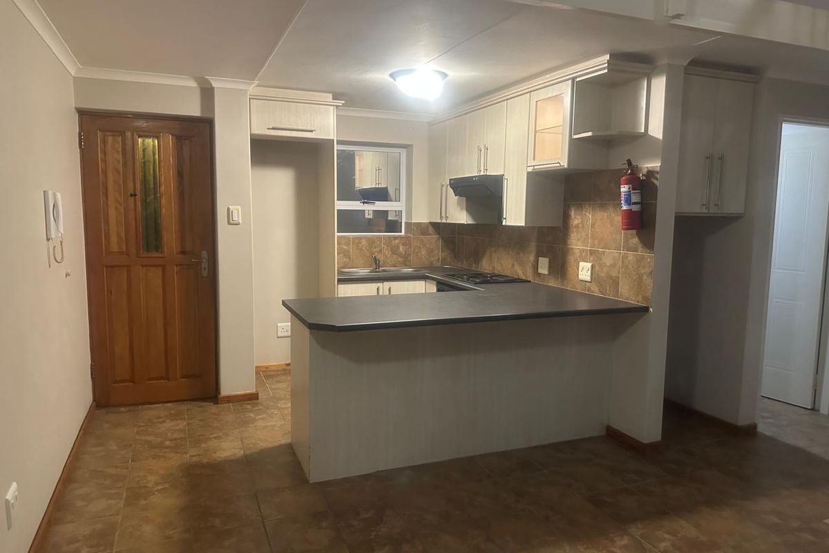 Functional kitchen featuring built-in cabinetry, laminate countertops, a hob with extractor fan, and tiled backsplash, offering a practical layout for daily use.
