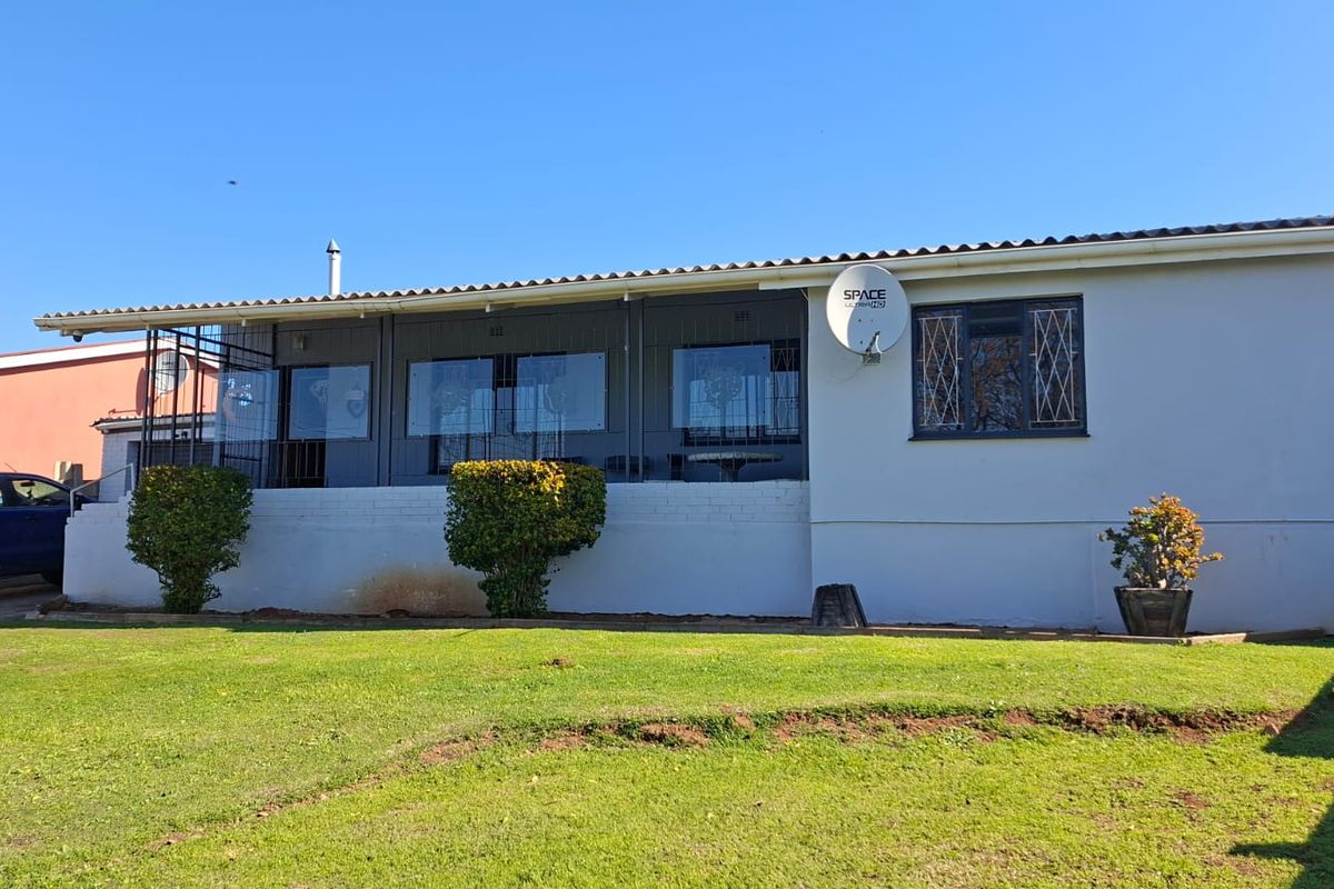 Rear view of the house featuring an enclosed patio area, security bars on windows, and a well-maintained lawn.