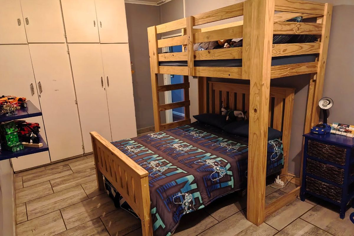 A bedroom featuring built-in cupboards and tiled flooring, providing functional storage and durable finishes.