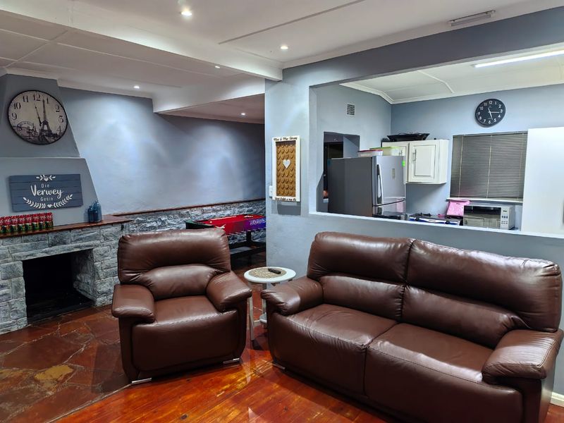 Open plan living area featuring a stone fireplace, wooden flooring, and a pass-through window connecting to the kitchen space.