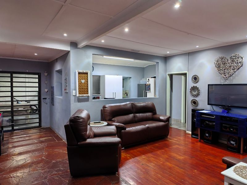 Open plan living area featuring a mix of stone and hardwood flooring, recessed lighting, and a convenient pass-through window connecting to the kitchen.