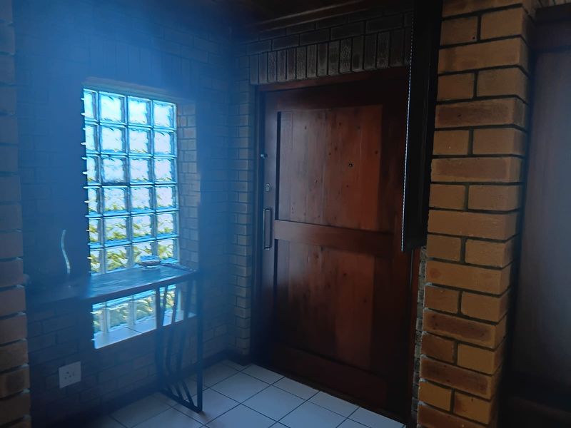 Entrance area featuring face brick walls, a solid timber door, and a decorative glass block window with ceramic floor tiles.