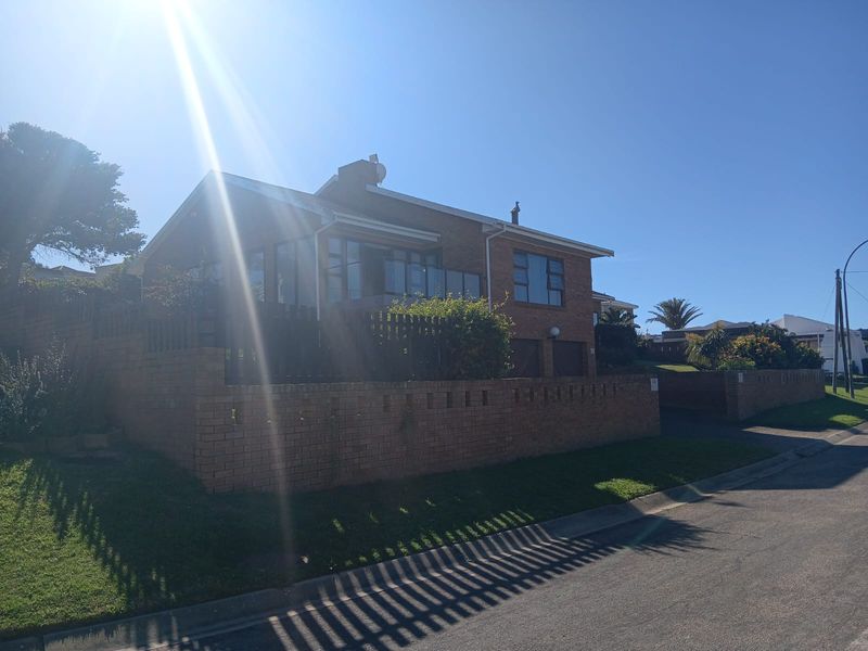 Front view of a double-story brick house featuring a double garage, boundary wall, and paved driveway in a residential street setting.