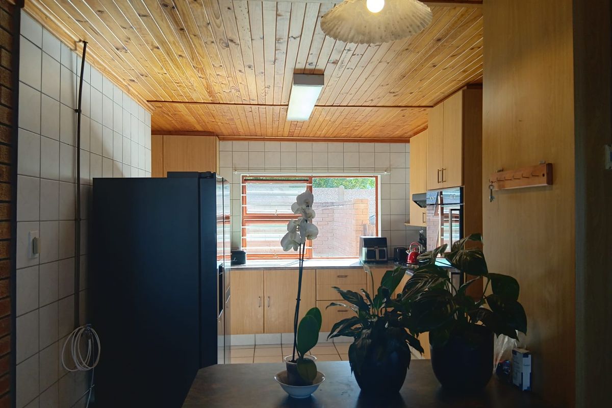 A functional kitchen featuring wooden tongue and groove ceilings, tiled splashbacks, and built-in cabinetry with an integrated oven and extractor fan.