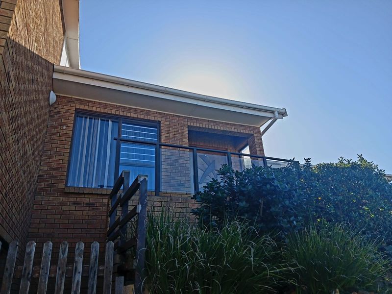 An elevated balcony featuring a modern glass balustrade and brick exterior wall, providing an outdoor space accessible via sliding doors.