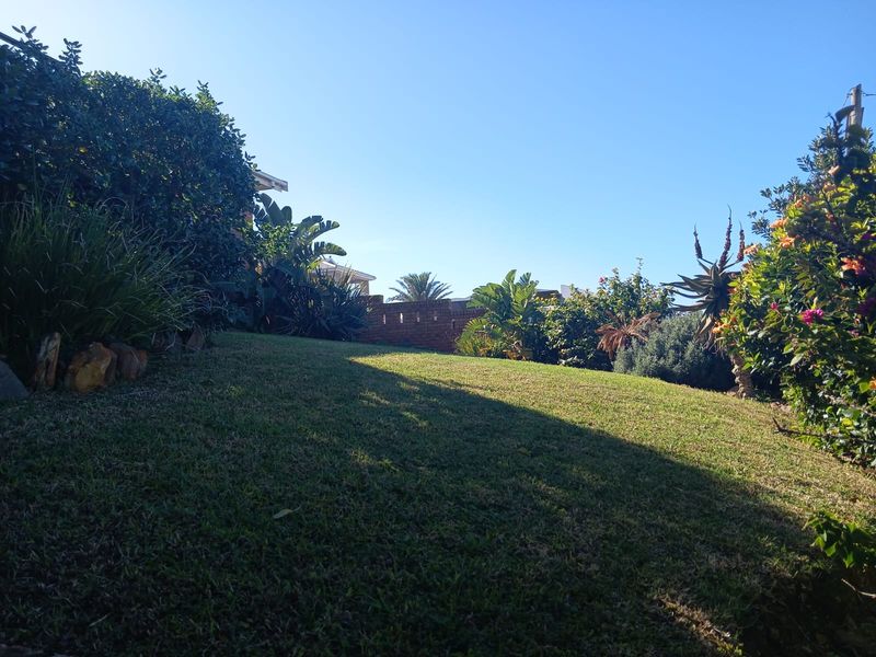 A well-maintained, sloping garden area featuring established greenery and a brick boundary wall, providing a private outdoor space.
